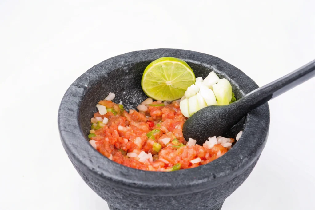 Grinding garlic and chilies in a molcajete to make salsa